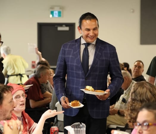 A man in a blue suit holds two plates of food.