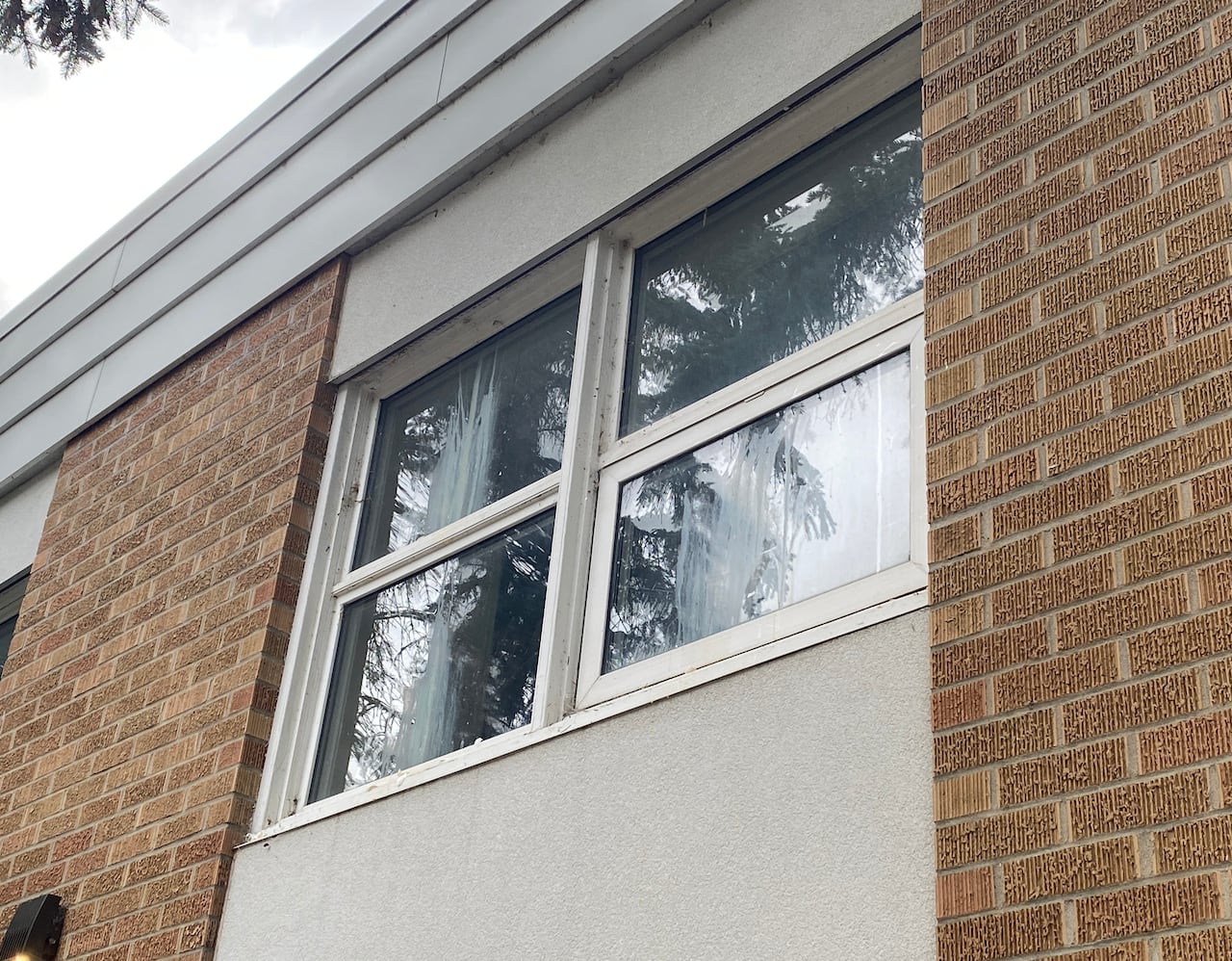 Four high window panes on a brick building, with streaks left by raw eggs.