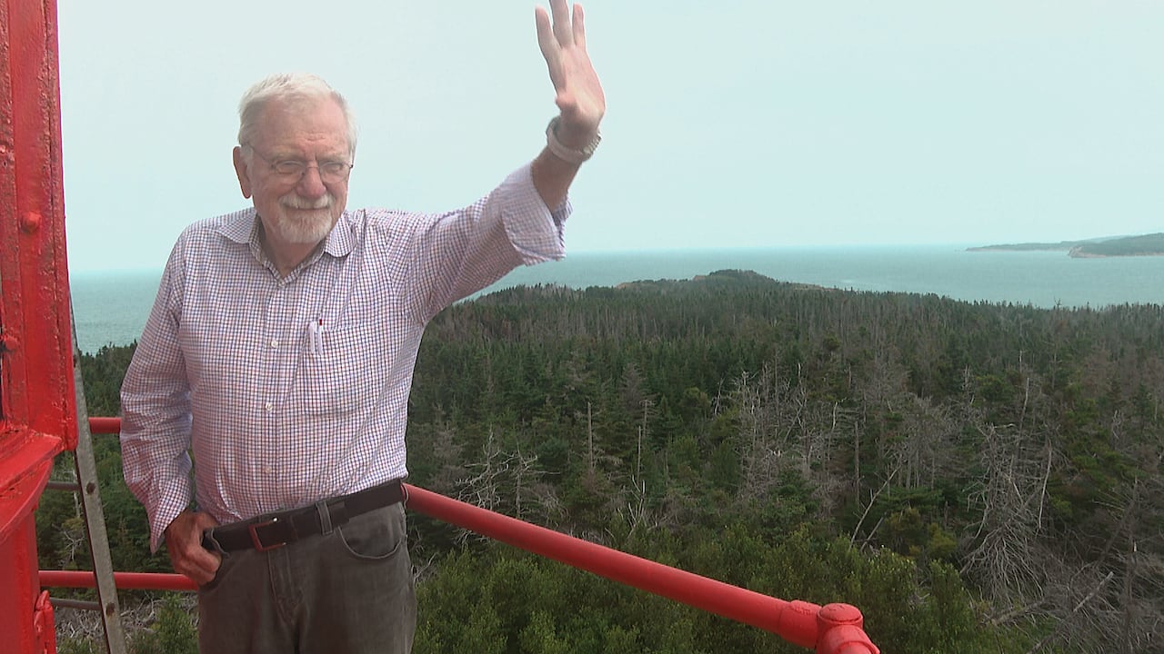 William F. Baker waves down to his wife and friend, as he stands on the top of his lighthouse on Henry Island on August 16.