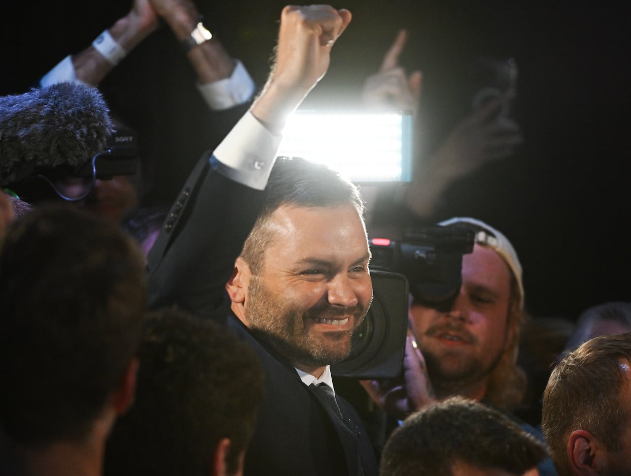Man in suit with fist in the air, smiling.