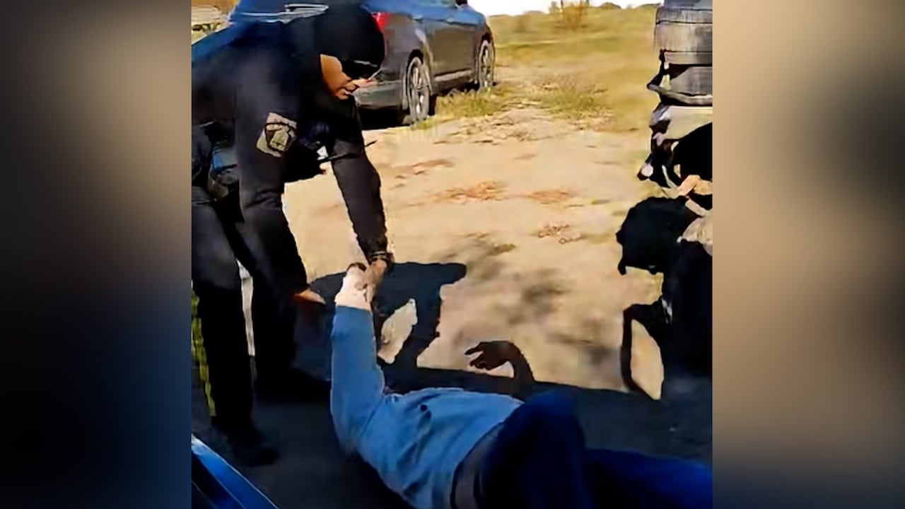 a police officer holds onto the arm of a man lying on the ground