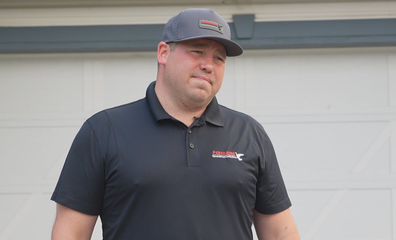 A man stands in front of a house.
