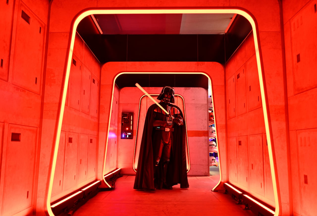 person in star wars darth vader costume stands surrounded by red lights