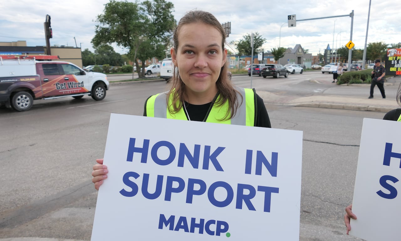 A woman holds a sign that says 'honk in support.'