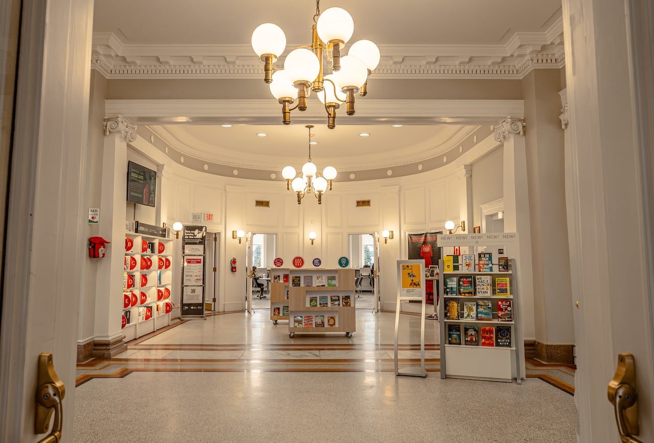 A bright, white-walled foyer with high ceilings and stacks of books.