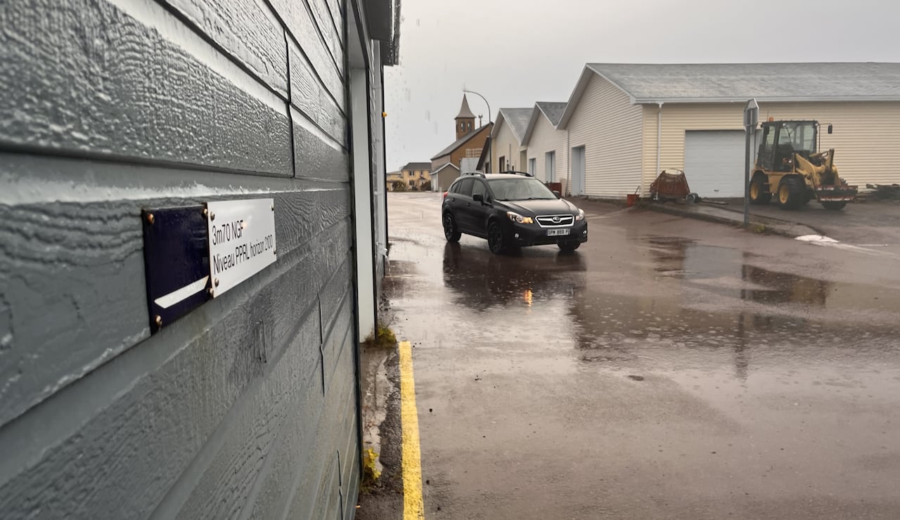 A sign on a building, on a rainy street.