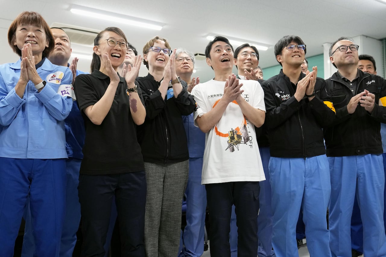 People in blue and black clothing clap, smiling