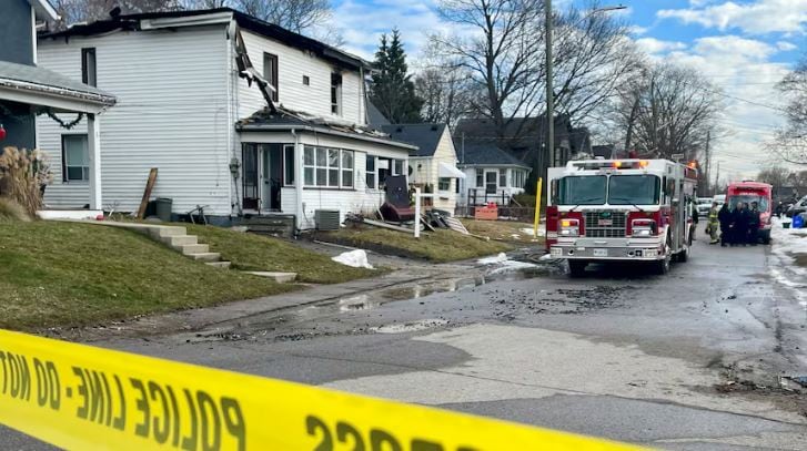 A home that's been destroyed by fire is shown. A firetruck is parked in front of the home behind police tape.