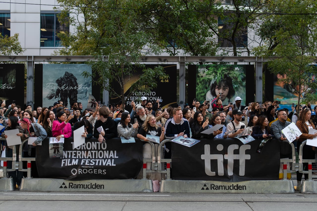 Crowd of people cheering behind a bar with a black sign that reads "TORONTO INTERNATIONAL FILM FESTIVAL."