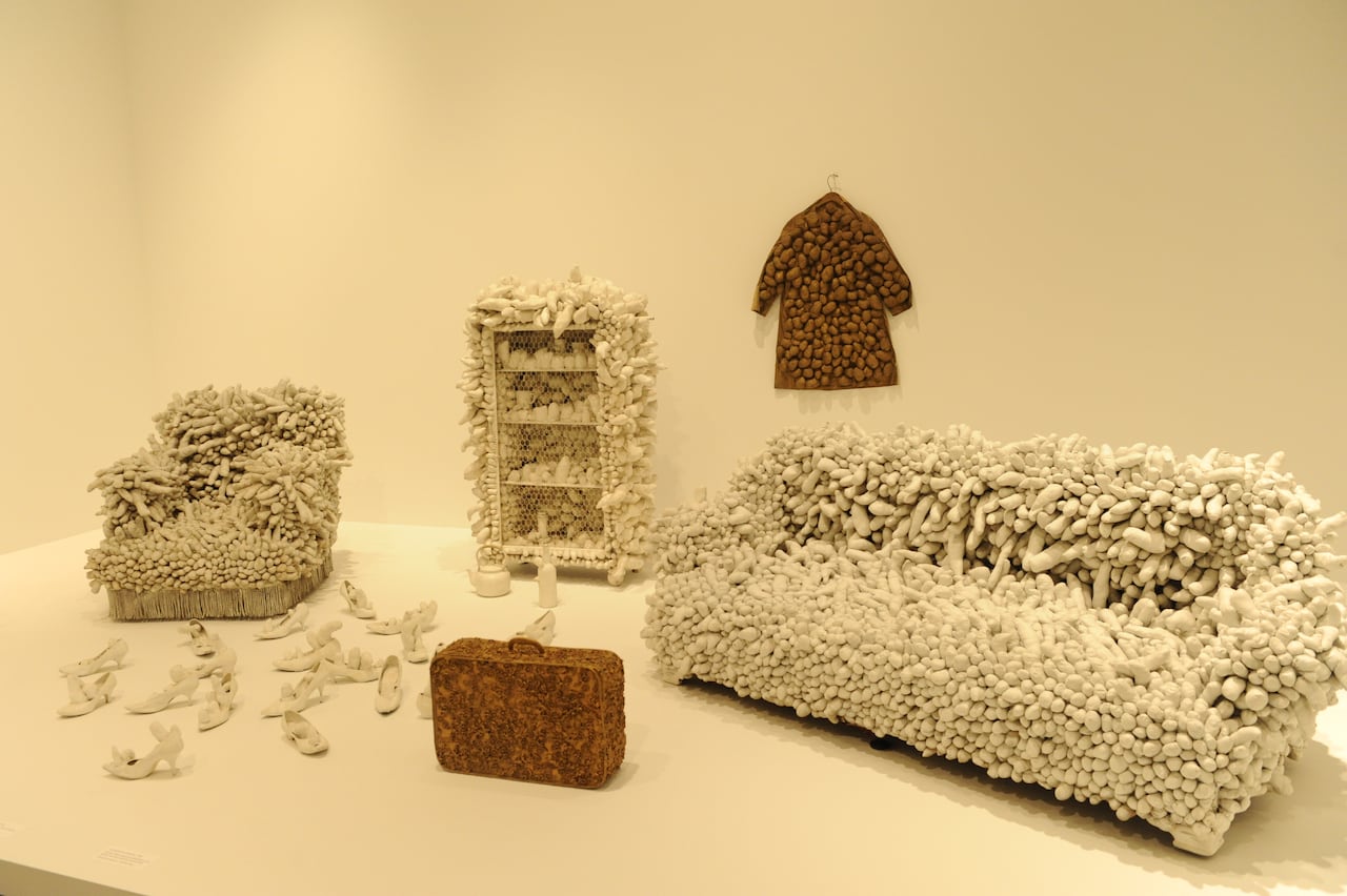 an art installation showing a couch, clothes, a suitcase and other objects covered in phalluses.