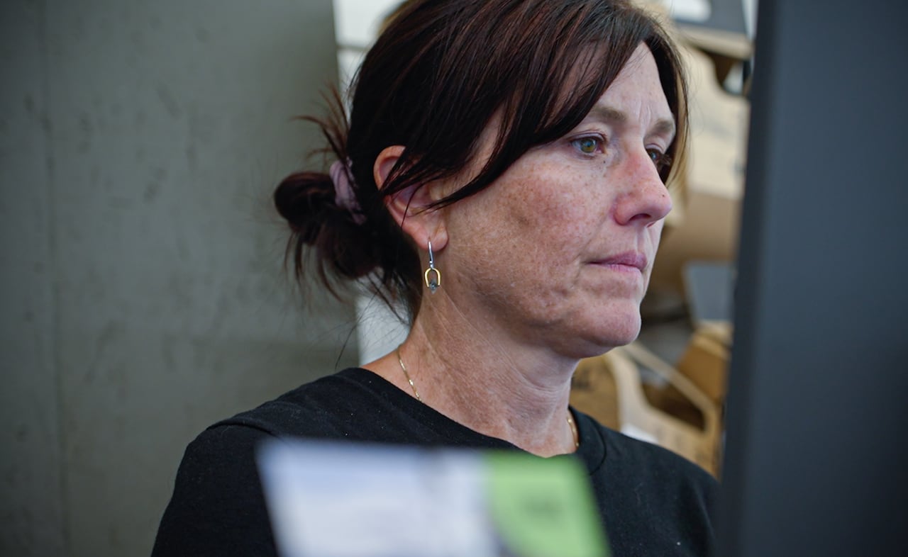 A woman with her brown hair tied back, wearing a black top.