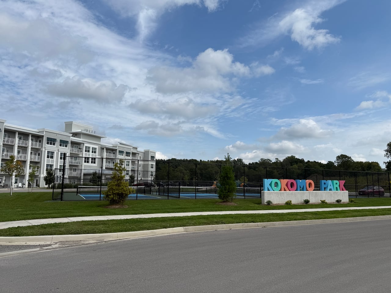 a pickle ball court in front of a condo with a sign saying Kokomo Park
