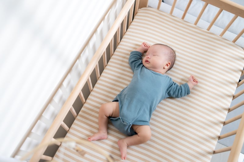 An image provided from the federal government shows an example of safe infant sleeping practices. A baby asleep on their back in an empty, wooden crib. The crib has a firm, snug-fitting mattress, and a fitted sheet. The baby is wearing a onesie. (Courtesy of the Government of Canada)