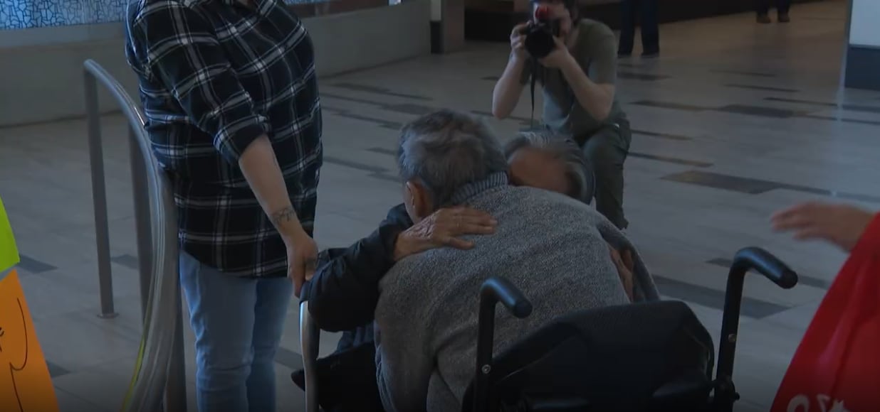 Two people in wheelchairs embrace.