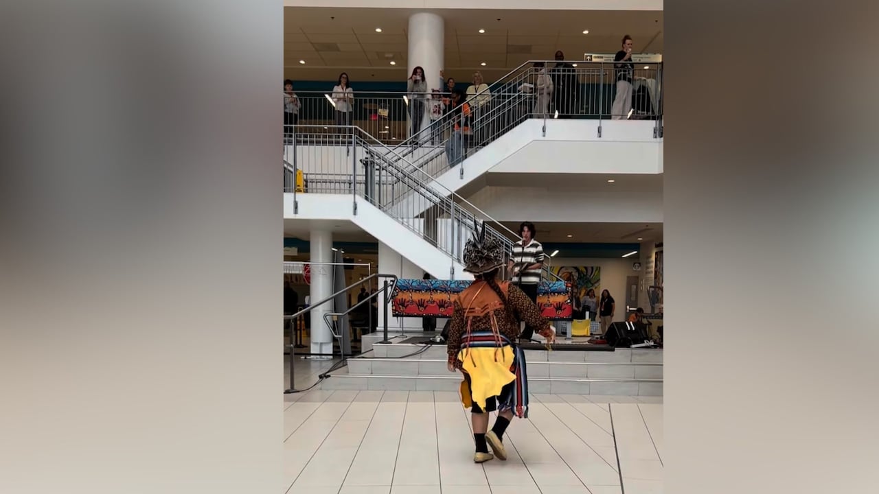 A boy performs in a hospital foyer while people watch