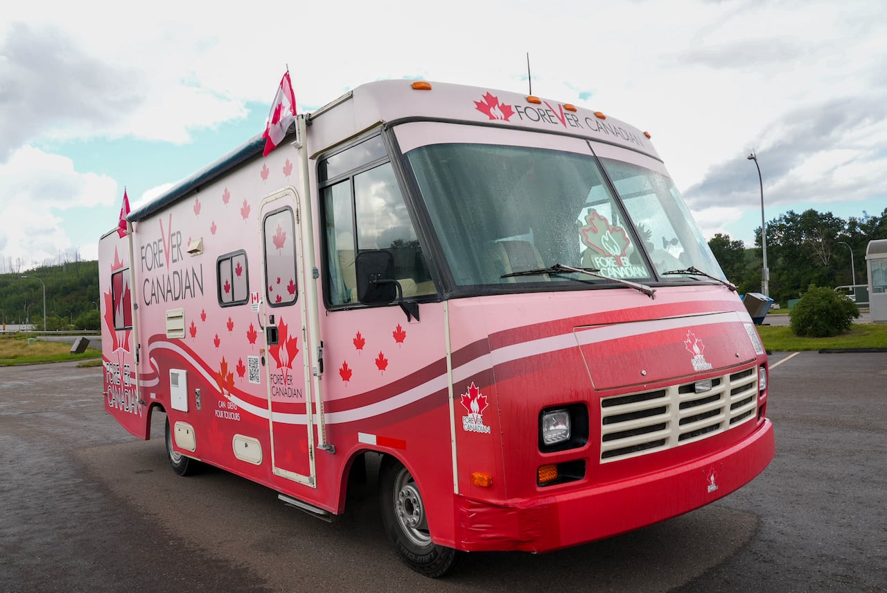A red and pink bus with red maple leaves and "Forever Canadian" written on its sides.