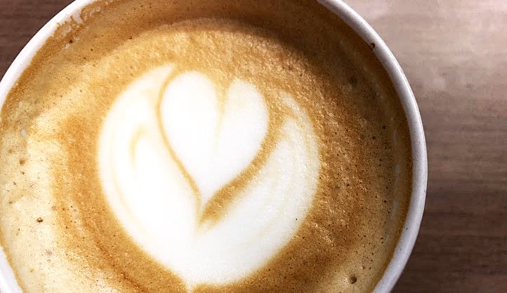 A cup of latte with a heart designed in the foam.