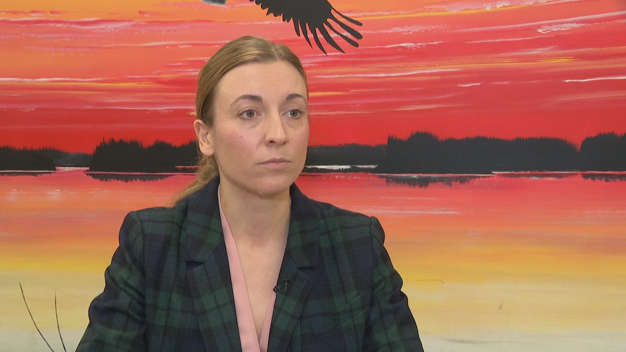 A woman in a blazer looks at the camera.