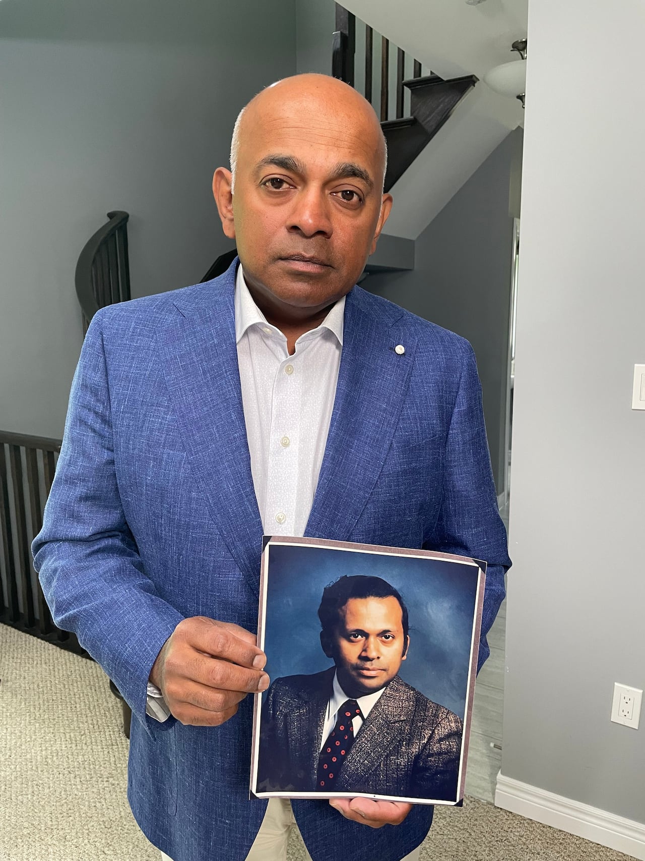 Rob Alexander holds a photo of his father, Anchanatt Alexander at his family home in Hamilton, Ont. 