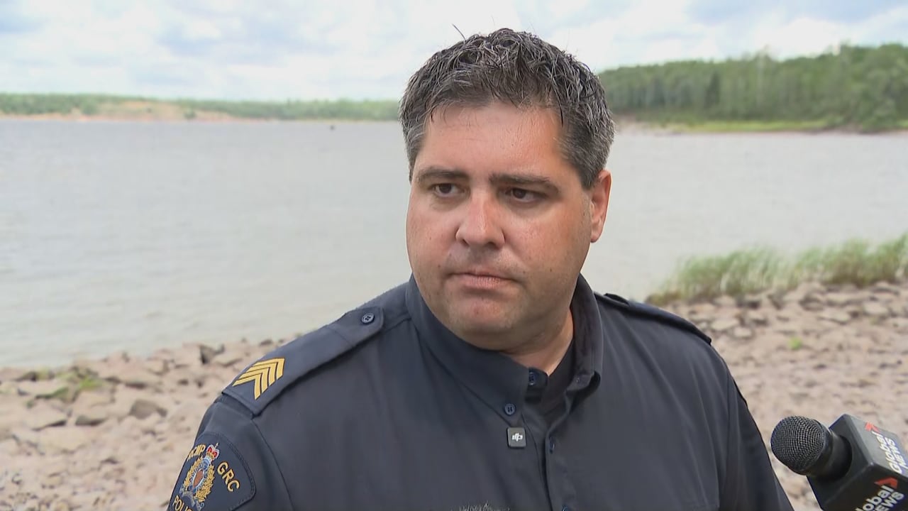 An RCMP officer looks solemn as he stands near a shore where two boys are believed to have drowned.