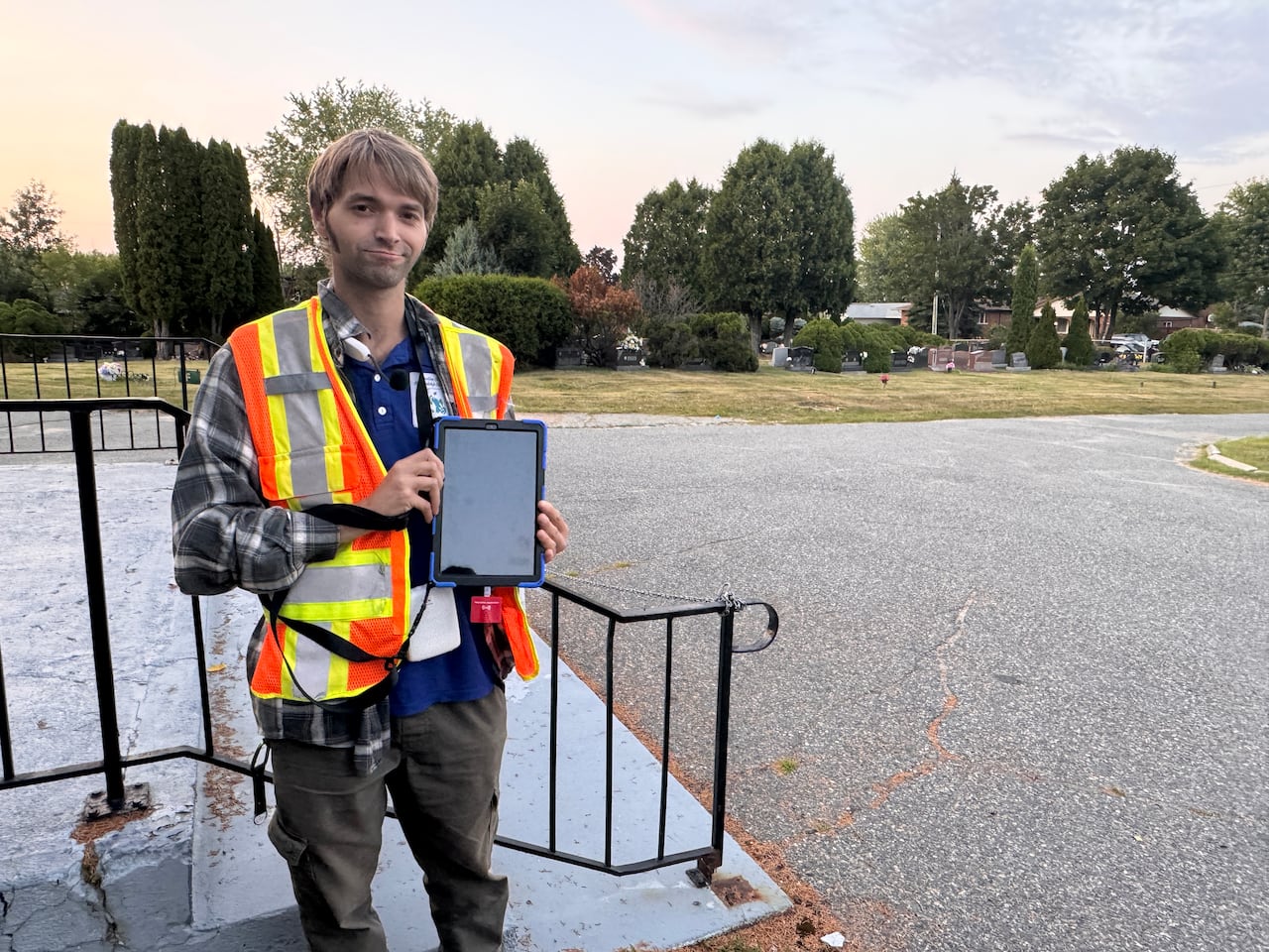 A man in a flannel is holding an iPad.