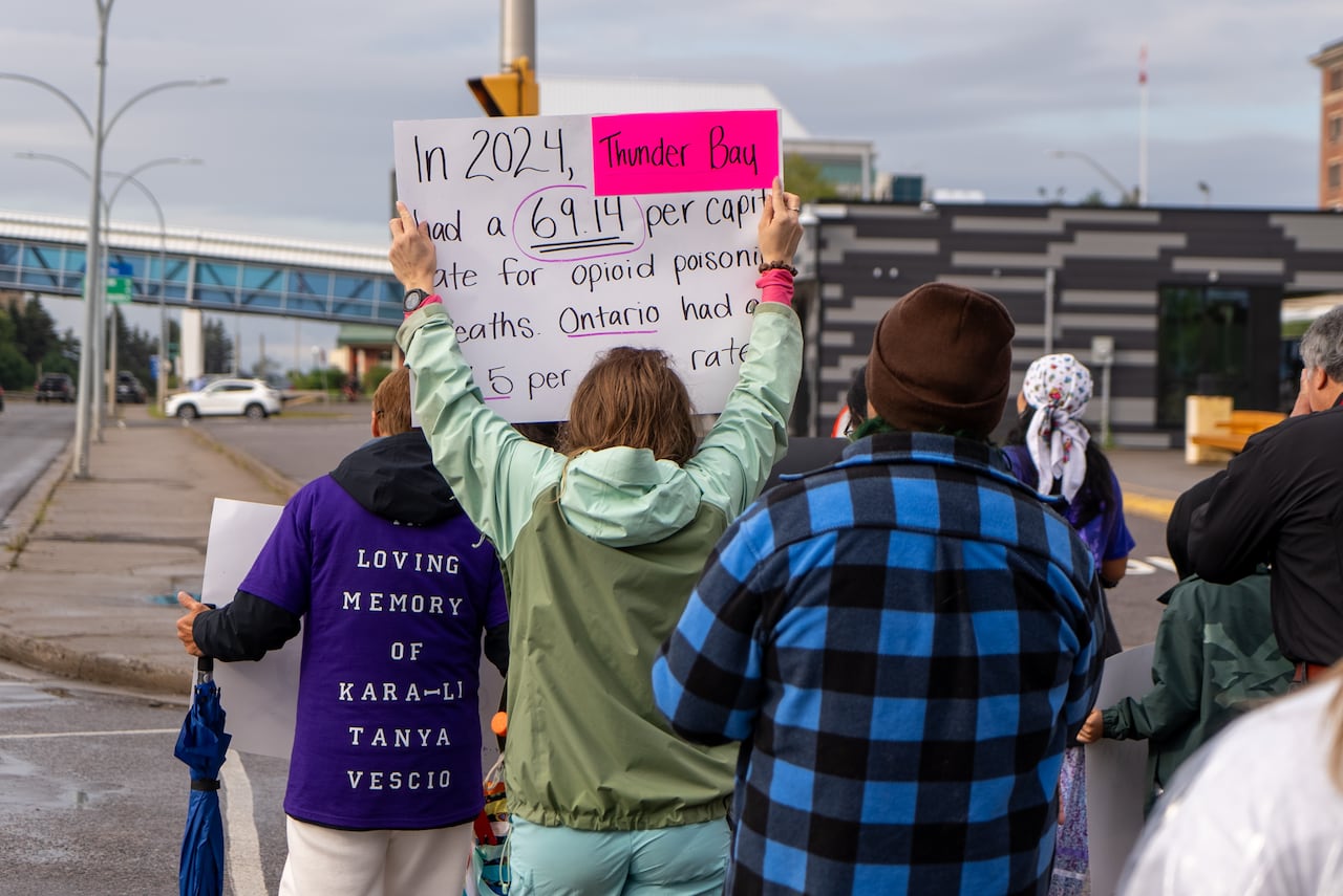 A group of people walking with signs is seen from behind.