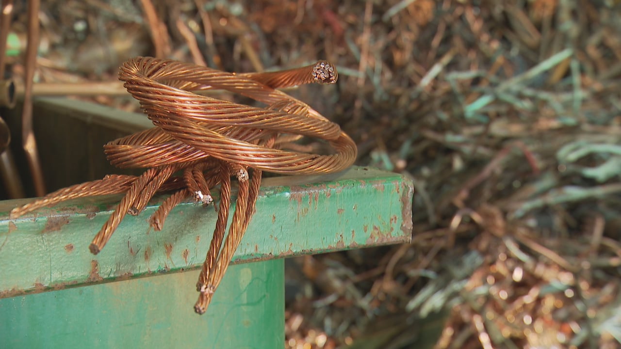 A spool of copper cables is seen on a green slab.