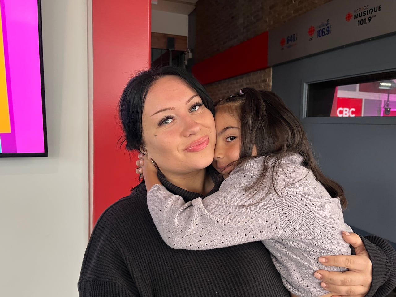 A woman in black holds her daughter tight.