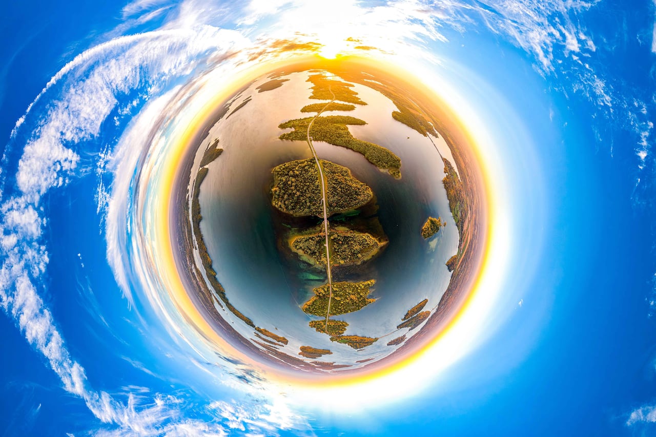 A planet-like orb surrounded by an orange ring is filled with a roadway connecting several islands.