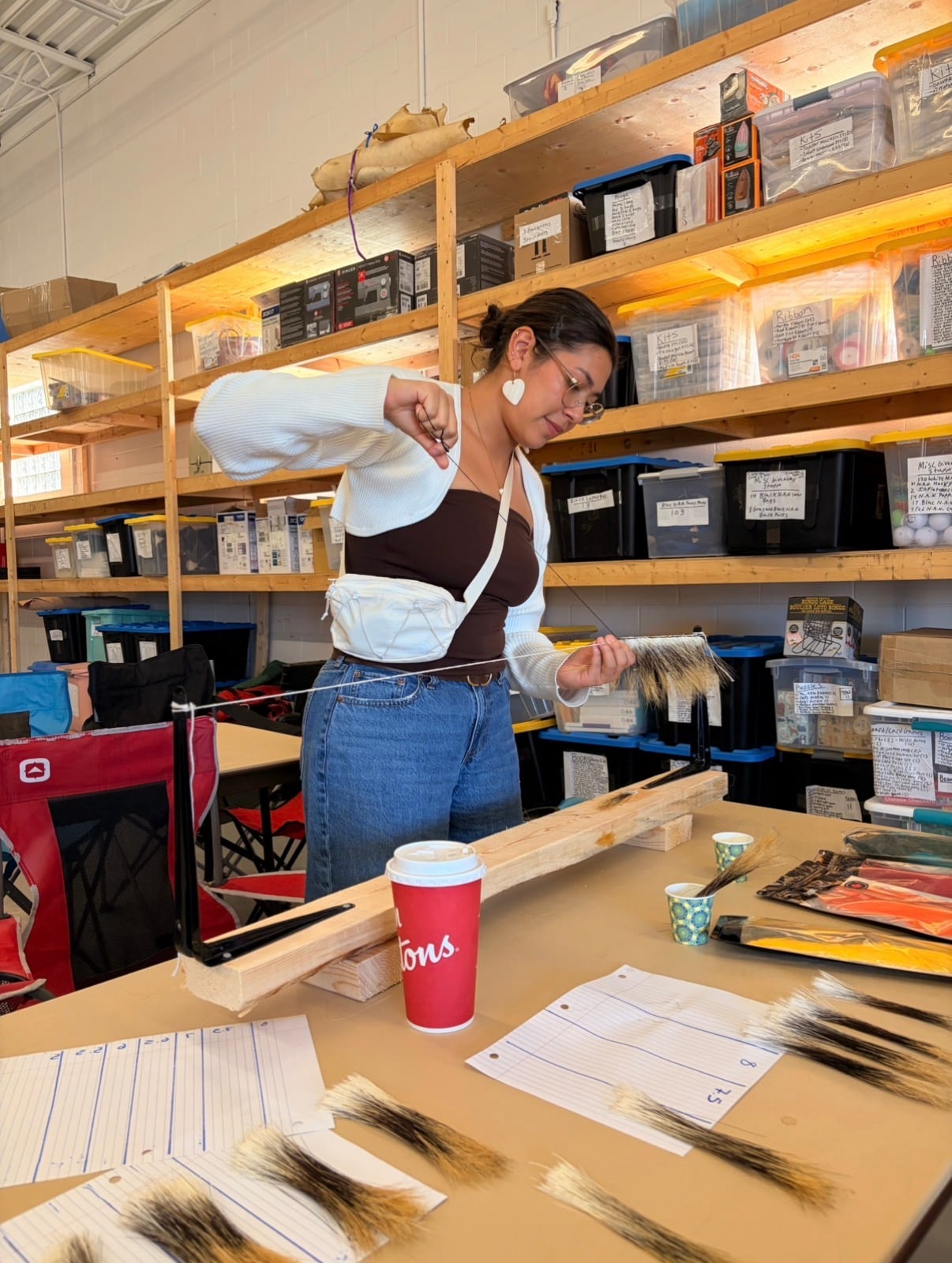 Tisha Duncan stands working on a regalia item for the Wabinoong Regalia Collective