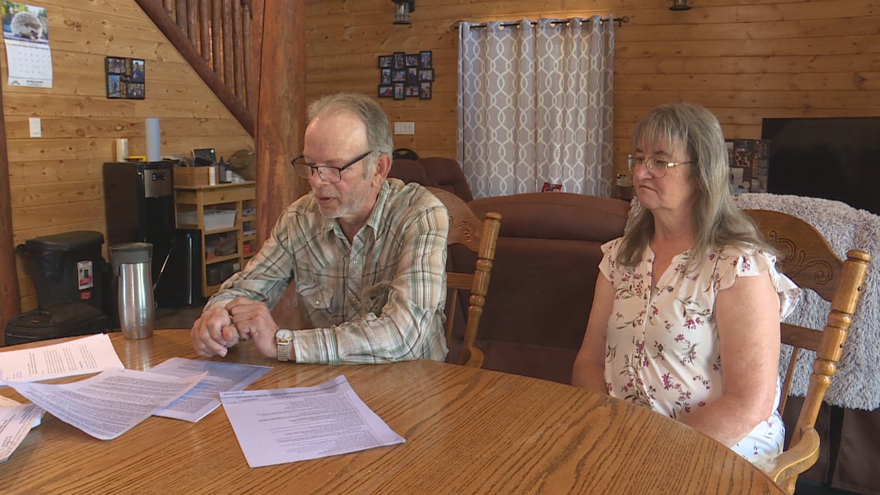 Two people sit at a table with papers on it.