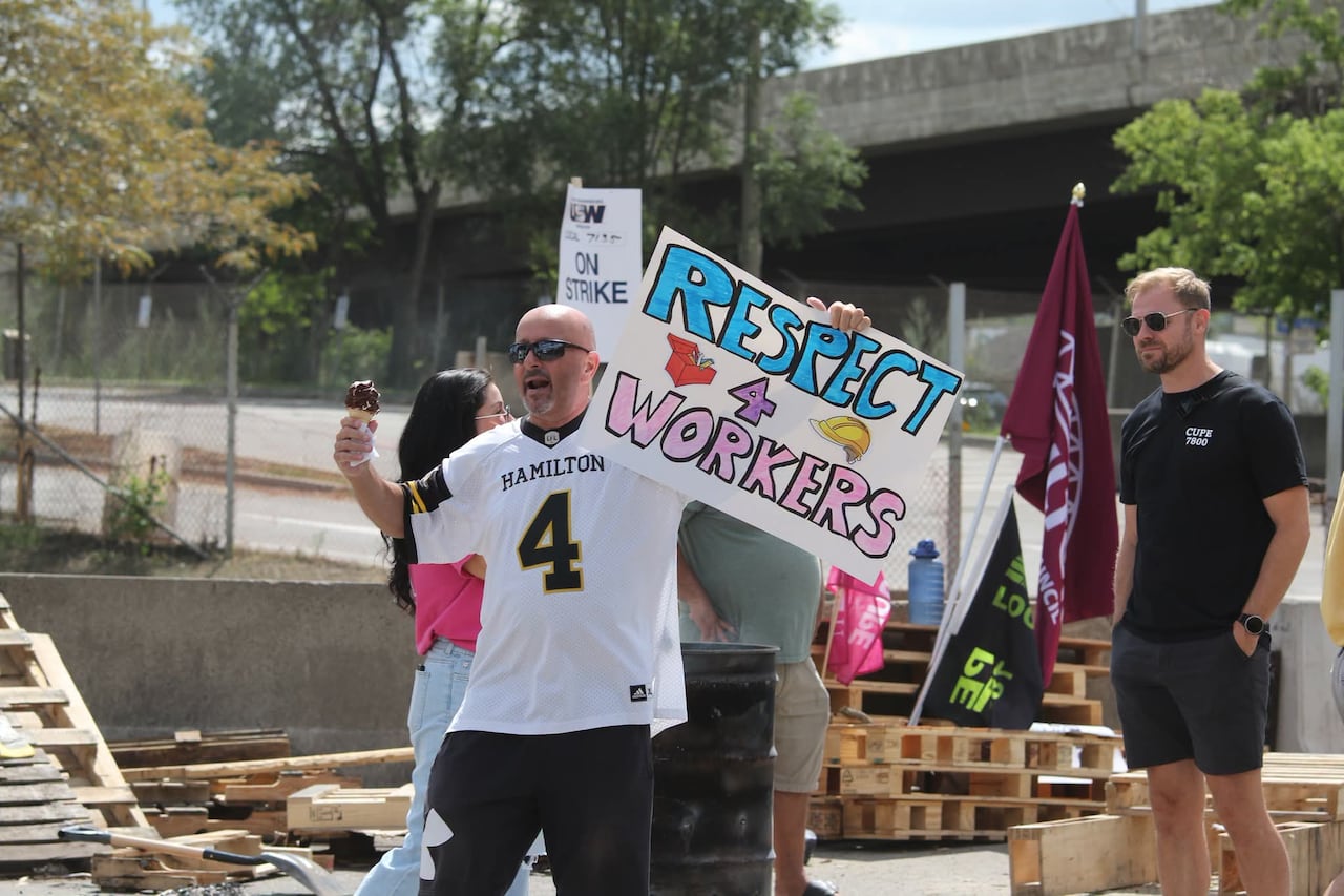 A man holds a sign in one hand that says "respect 4 workers" and an ice cream cone on the other.