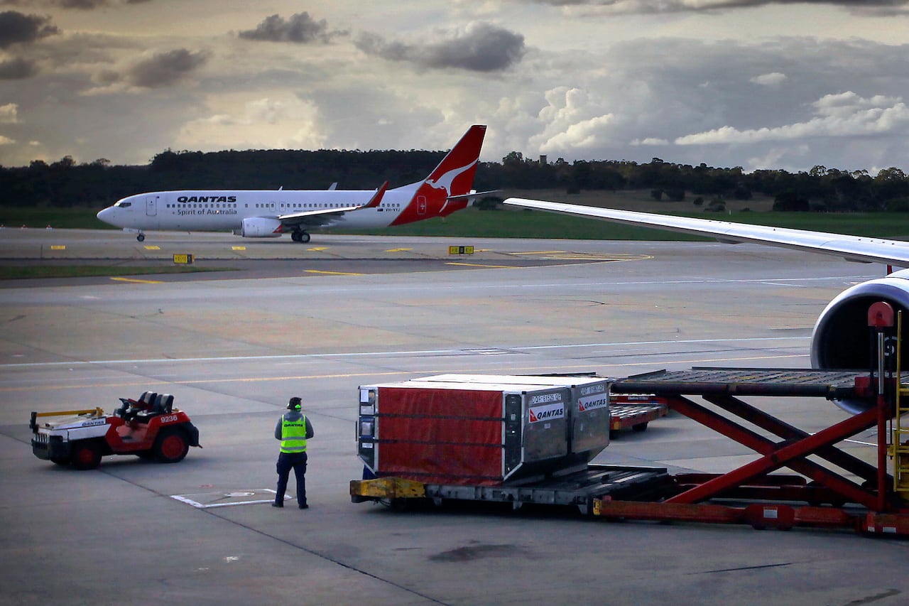 A worker on a runway with a large plane.