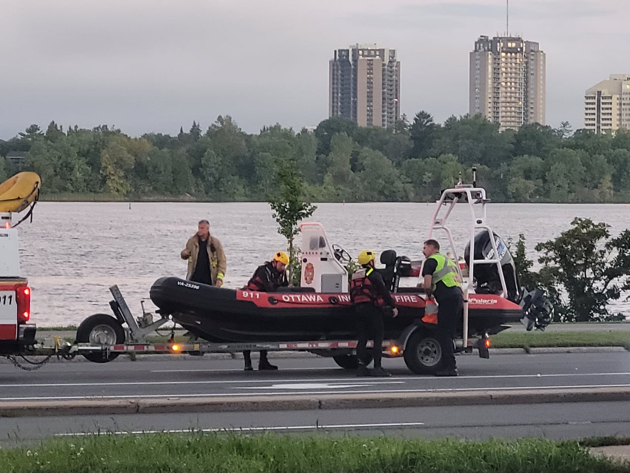 Emergency responders at a boat by a river on a summer morning.