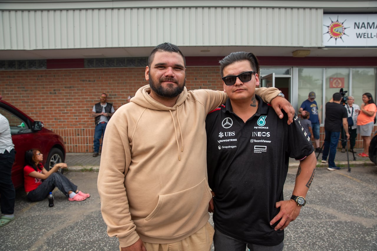 Two people are seen standing in a parking lot.