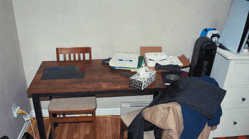 A table with a number of items on it, including a coil notepad with a handwritten letter and a pen on top.
