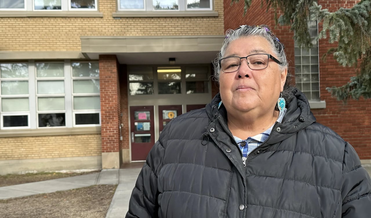 A woman stands in front of a school.