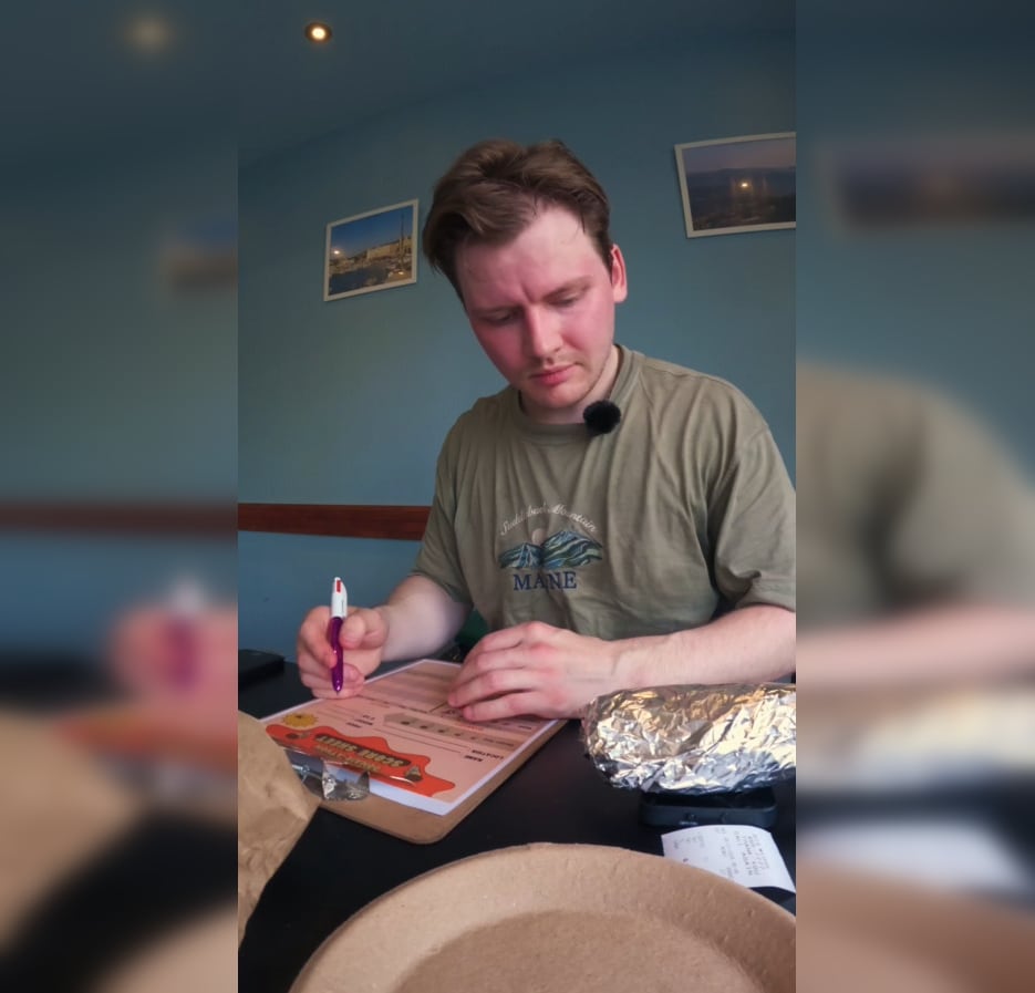 A young white man is shown with a clipboard making notes regarding the quality of the donair.