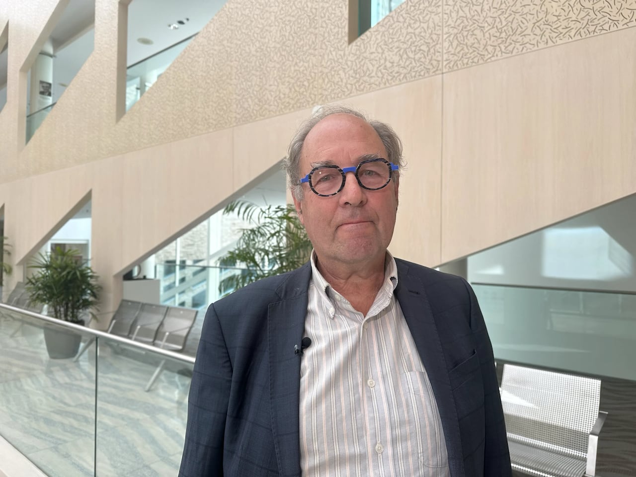 A man with grey hair wears glasses.