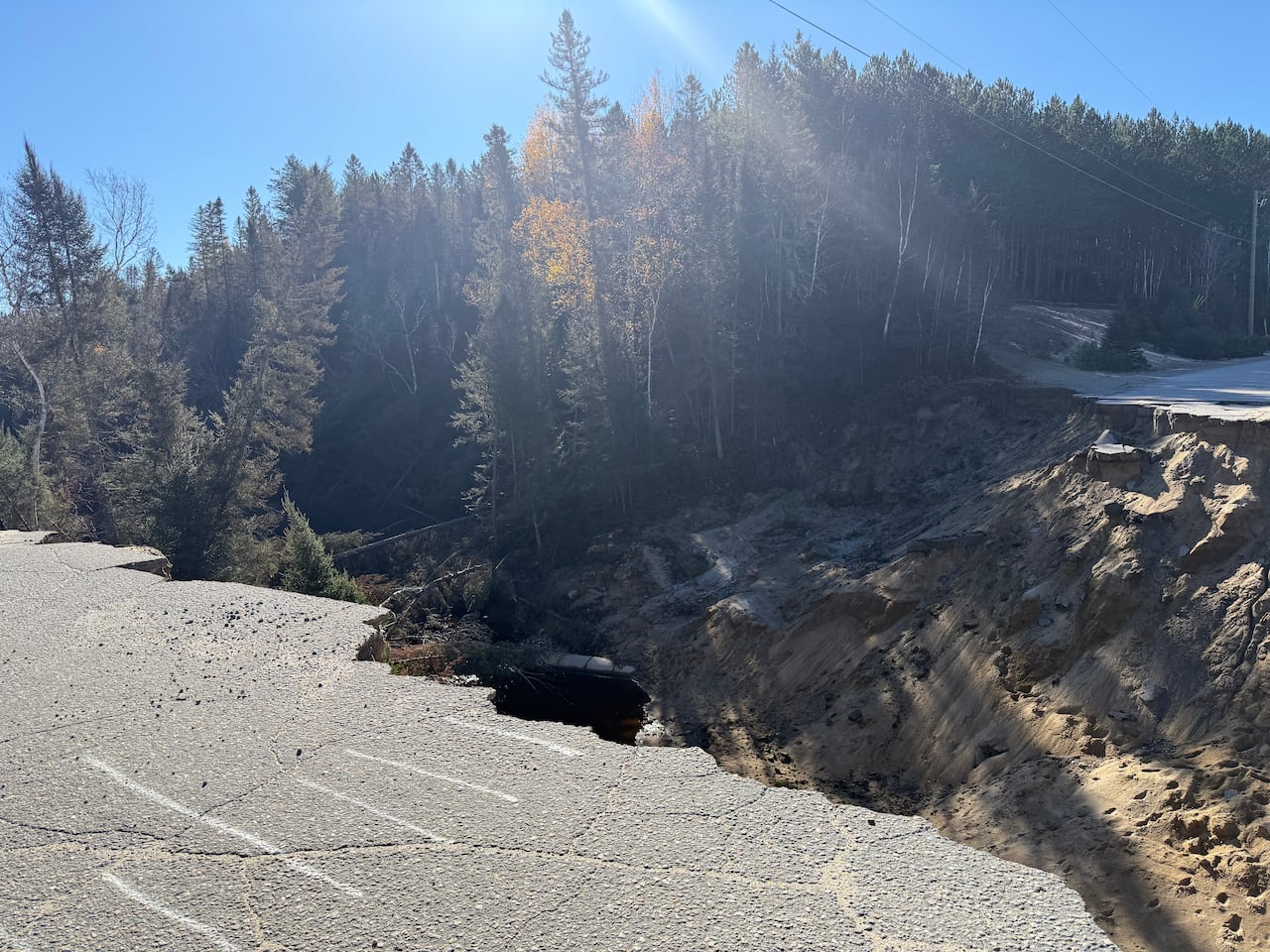A  crumbling road gives was to a giant crater across which you see the other side of the road.