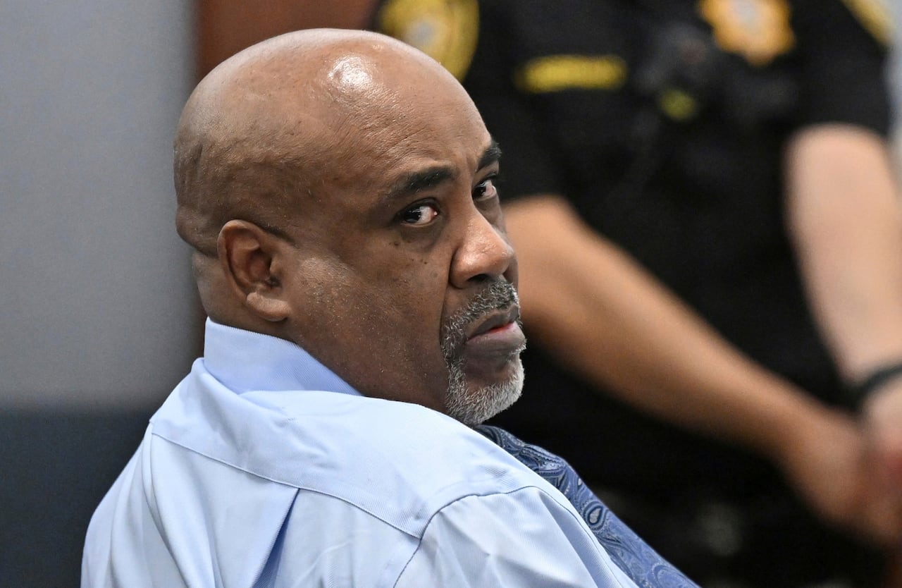 A man in a blue shirt looks back in a courtroom.