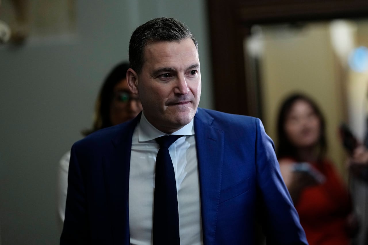 A man in a suit looks to one side.