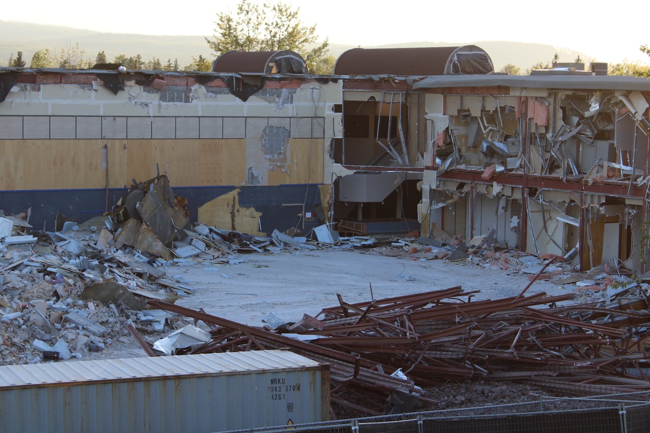 the inside of a half demolished school, exposing hallways and twisted metal and torn down walls laying in piles