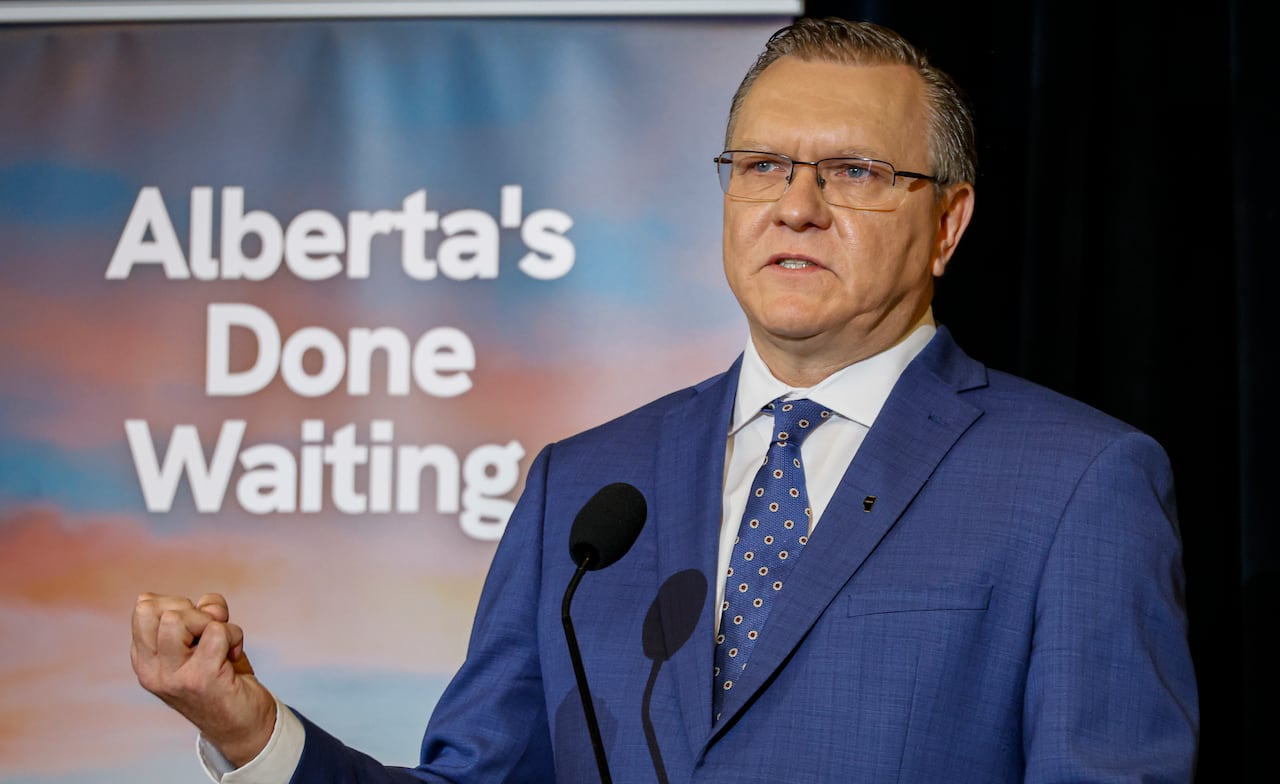 Person in blue suit and tie makes fist while speaking into microphone.
