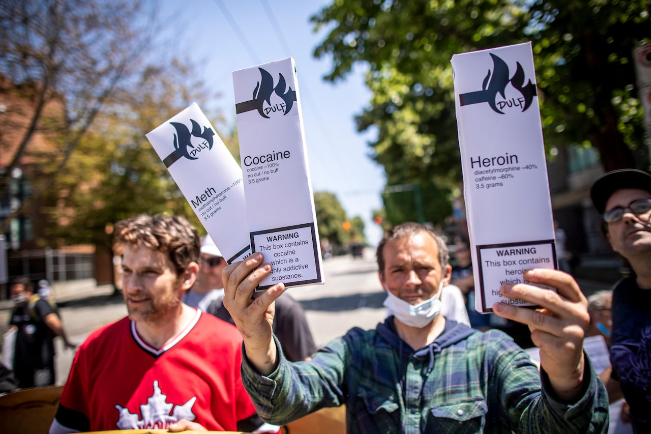A man holds boxes containing tested cocaine, meth and heroin from DULF in July 2021. (Ben Nelms/CBC)