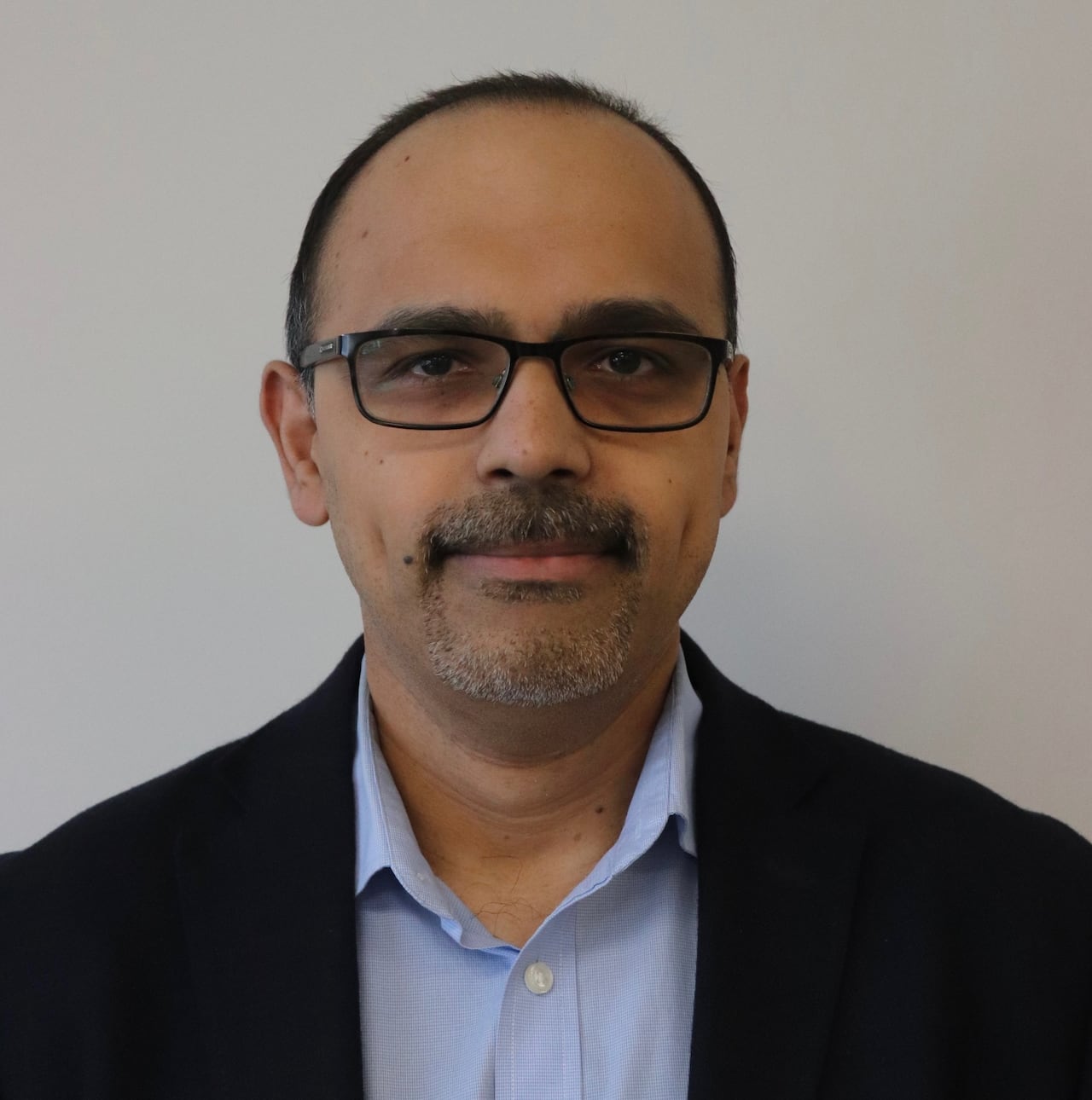 A spectacled man smiling