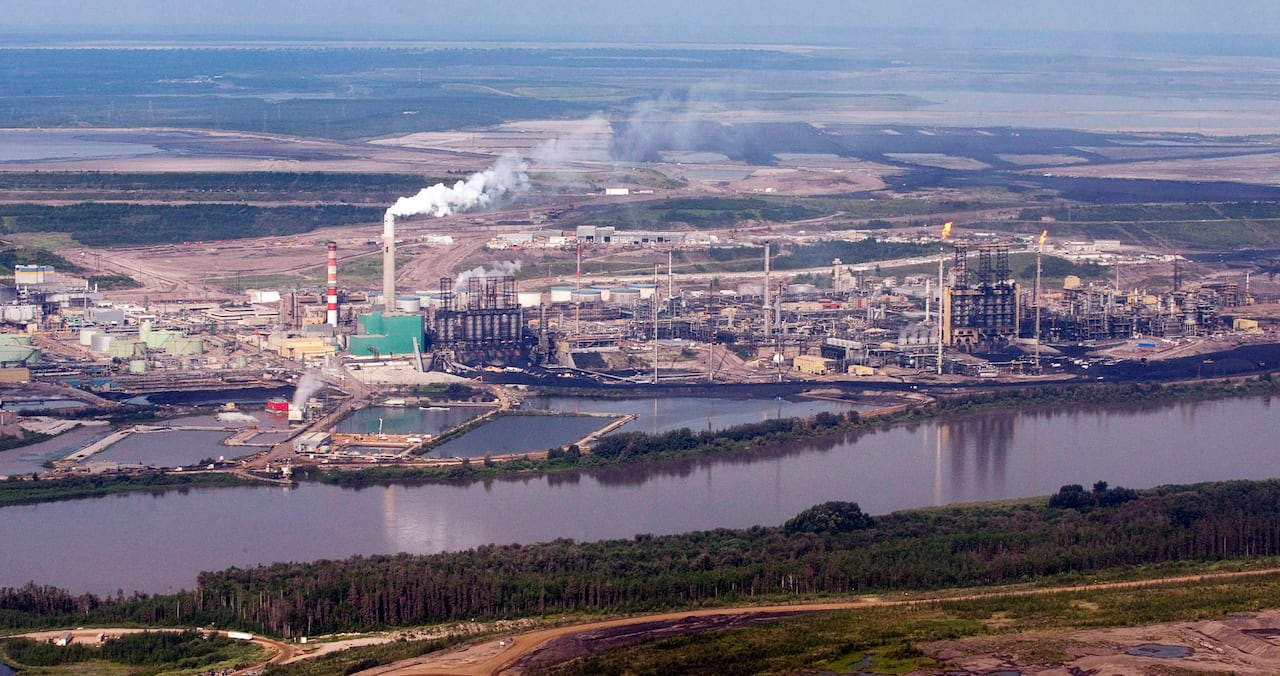 A river and forest sit next to an oilsands industrial site.