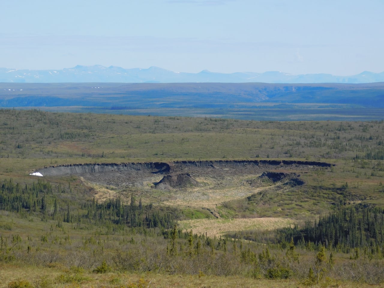 Overhead view of grasslands with one big area slumping inward.