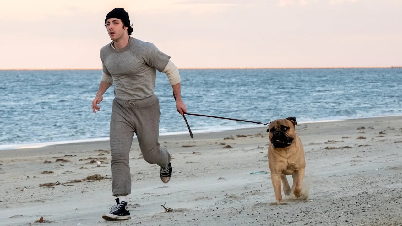Man runs along a beach with dog.