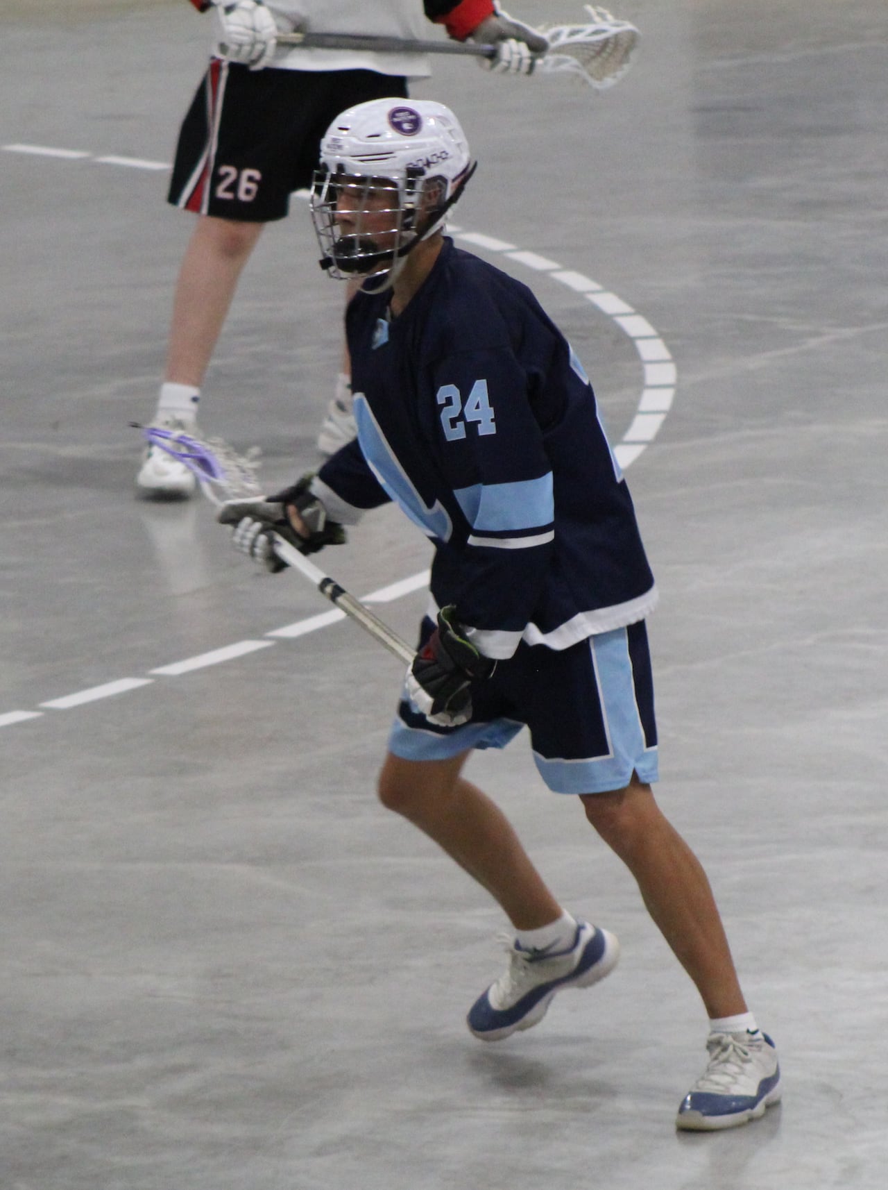 Lacrosse player faces opponents.